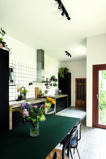 Le sol en terrazzo et le plan de travail en béton s'accordent bien avec la cuisine noire.