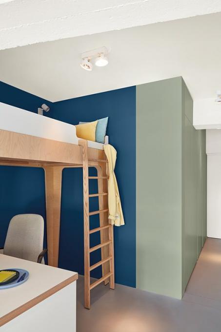Le renfoncement bleu fait ressortir le lit en bois et crée en même temps un sentiment de sécurité. 