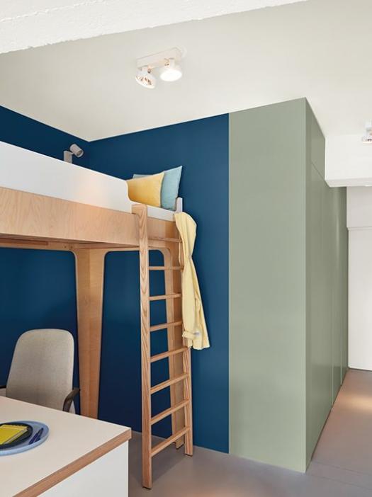 Le renfoncement bleu fait ressortir le lit en bois et crée en même temps un sentiment de sécurité. 