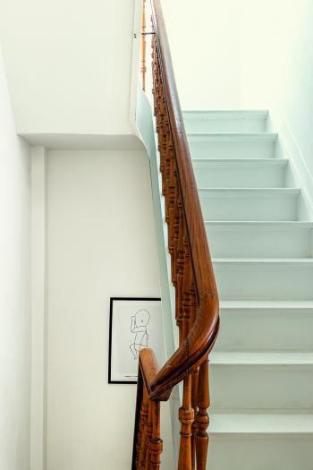 Een mooi contrast tussen de neutrale wittint op de muren en het hout van de trapleuning.