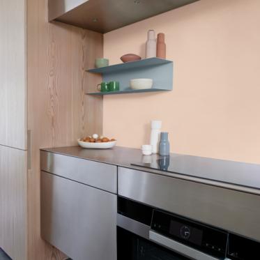 Een gedurfde keuken met pastelroze muur en houten kasten